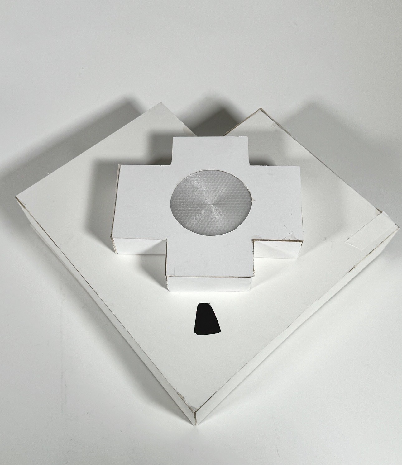 The white paper pill box from above, its centre dial silver