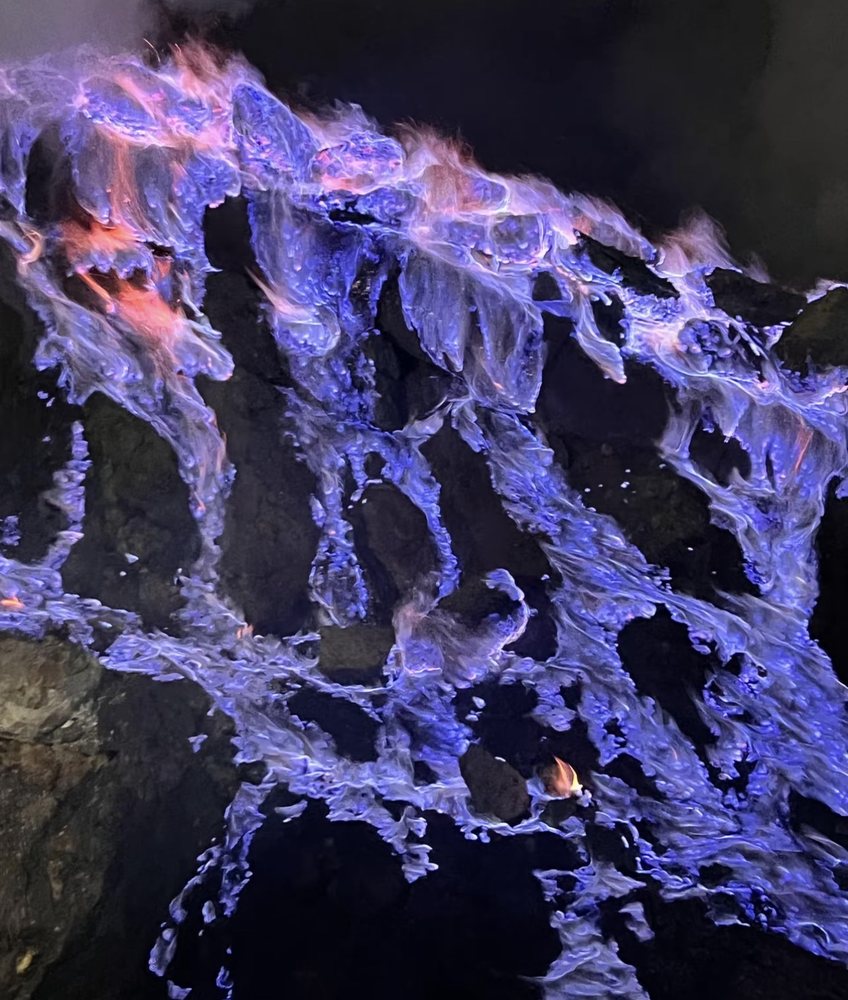 Blue fire flowing over dark rock